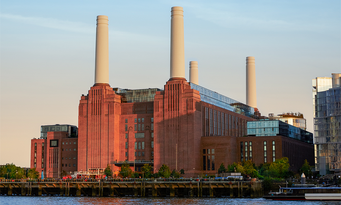 Widok z zewnątrz na ceglany budynek Elektrowni Battersea i jej cztery kominy.