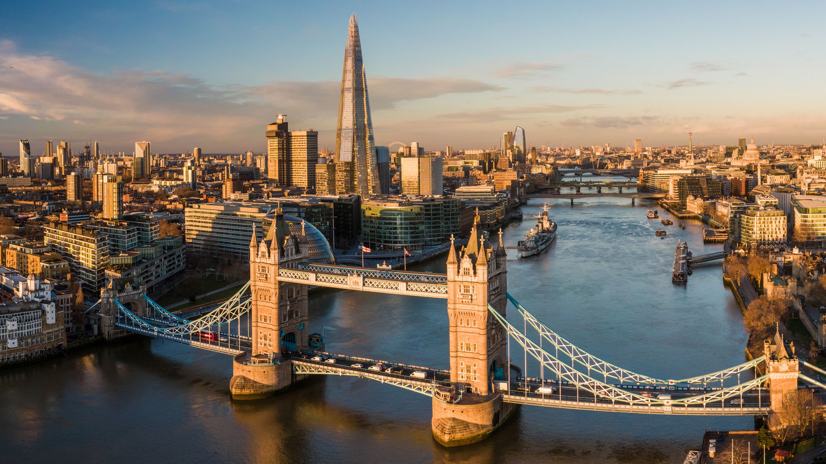 Zdjęcie z lotu ptaka przedstawiające Londyn i Tamizę. Na pierwszym planie widać most Tower Bridge.