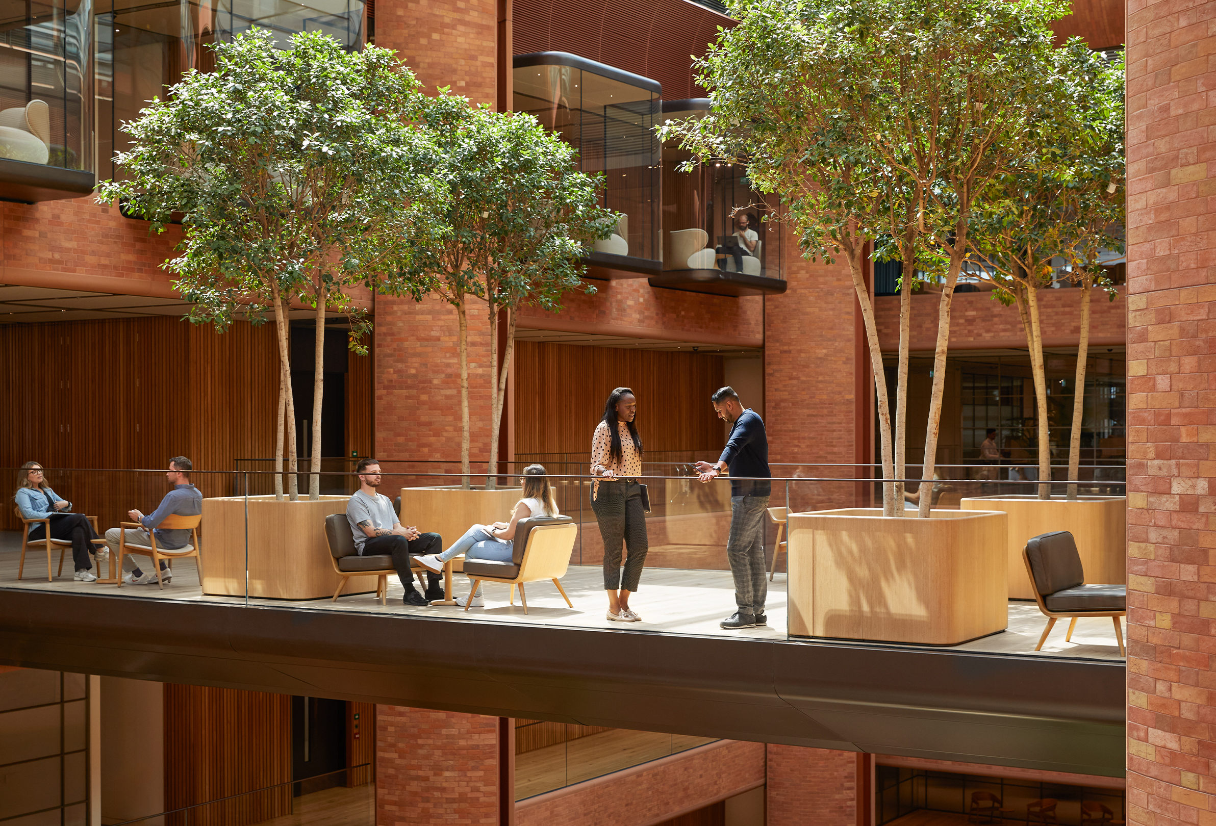 Wiele osób z zespołu Apple rozmawiających ze sobą w różnych grupach w atrium budynku Battersea.