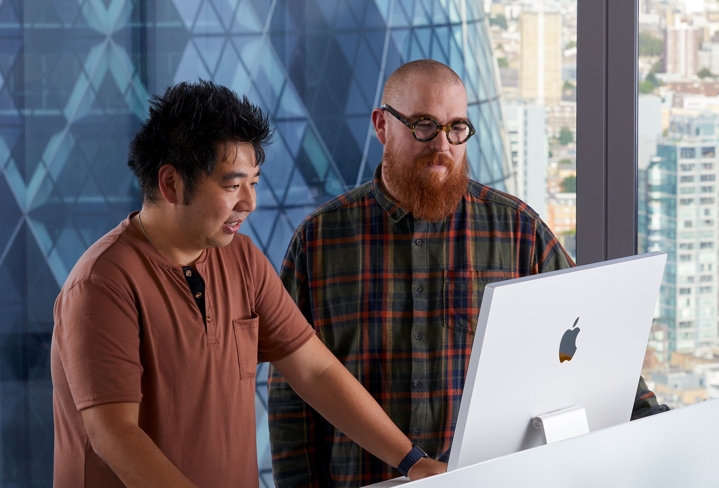 Dwie osoby z zespołu Apple podczas wspólnej pracy na iMacu.