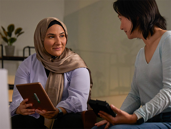 Deux membres de l’équipe Apprentissage automatique et IA d’Apple travaillent ensemble, l’un tenant un iPad et l’autre un iPhone.