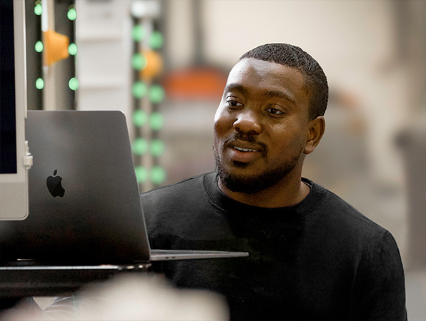 Dans une usine de fabrication Apple, deux personnes de l’équipe Apple examinent des coques de MacBook en aluminium sur des racks d’anodisation du titane.