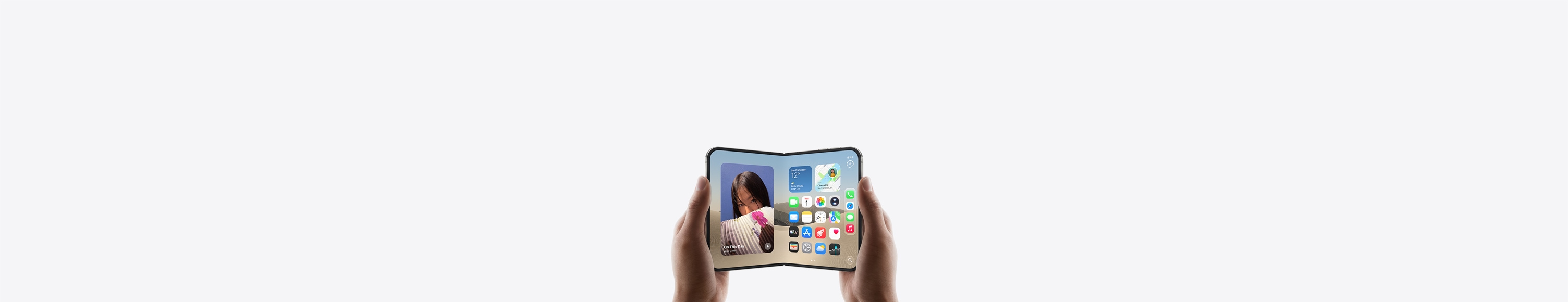 Két kézben tartott, fekvő tájolású, kinyitott iPhone Duo, a belső kijelzőn a főképernyő látható.