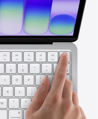 MacBook Neo, strieborná farba, s prstom na senzore Touch ID v pravom hornom rohu klávesnice